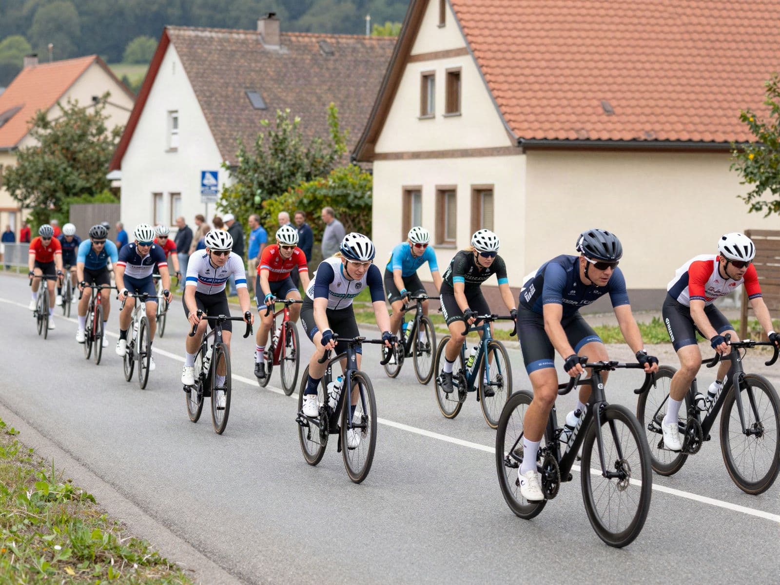 Junge Amateur-Rennfahrer:innen rollen kurz nach dem Start als Pulk durch eine deutsche Kleinstadt (KI-generiert)